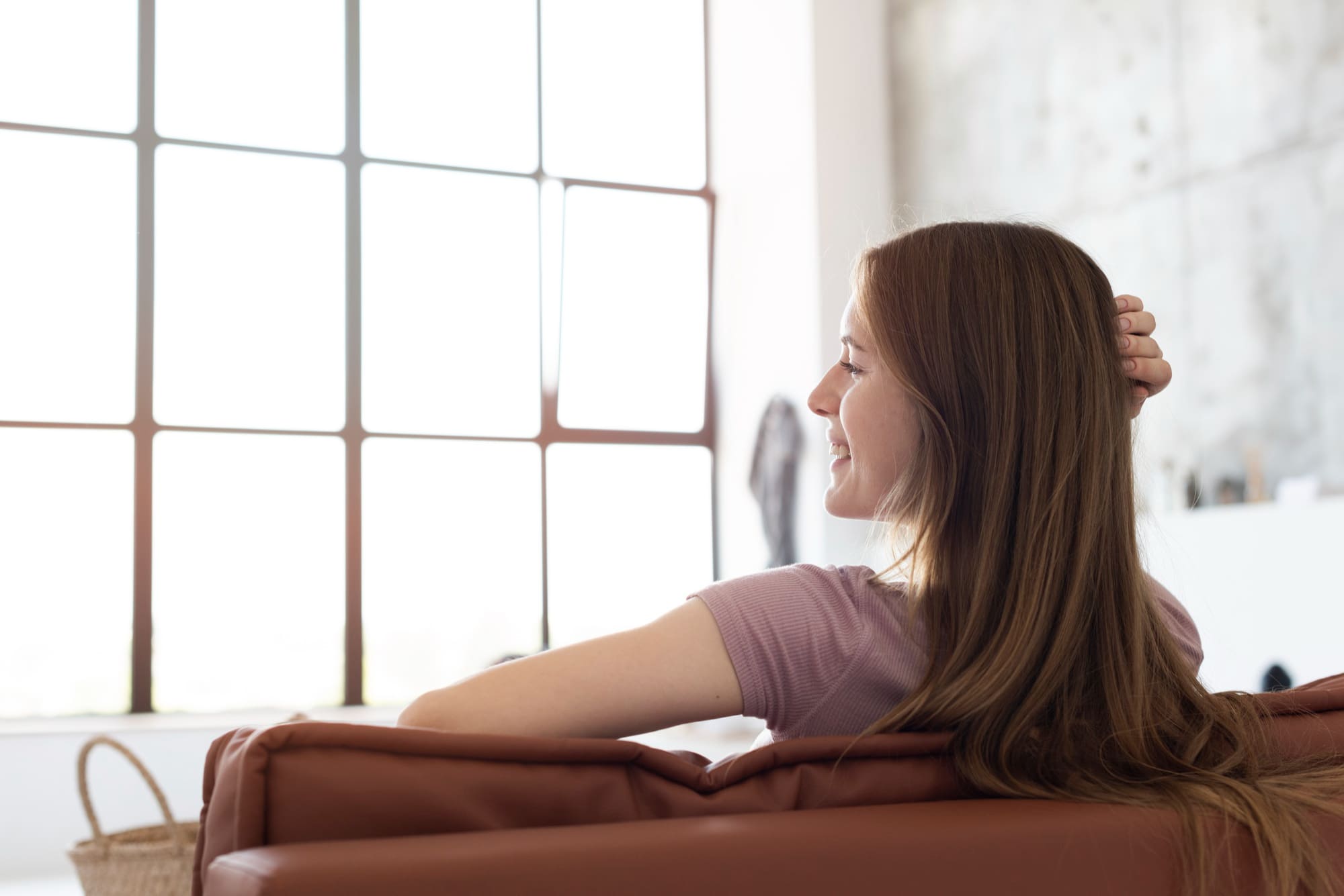 Woman relaxing on a sofa and enjoying natural light from a large window - LeaveConsult